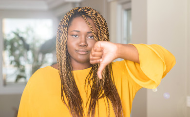 African american woman at home with angry face, negative sign showing dislike with thumbs down,...