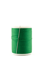 Spool of green thread and needle on white background