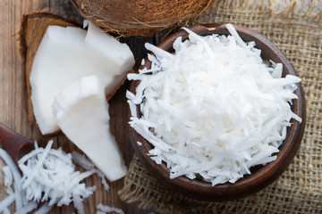 Coconut flakes in a clay bowl on a wooden rustic background. top view
