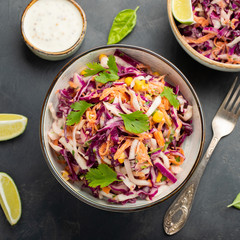 Purple cabbage and carrot salad with mayonnaise in a white bowl on a black background. Classic coleslaw. Diet vegetarian dish. Top view