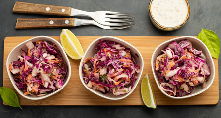 Purple cabbage and carrot salad with mayonnaise in a white bowl on a black background. Set of three classic coleslaw salad. Diet vegetarian dish. Top view
