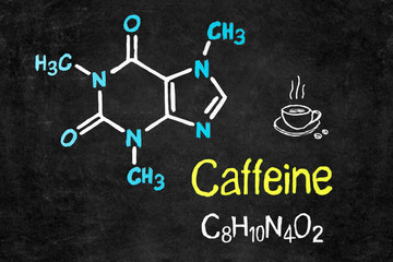 Handwritten chalk chemical formula of Caffeine on school blackboard.