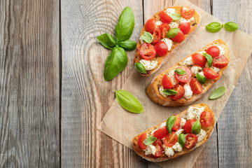 Bruschetta with tomatoes, mozzarella cheese and basil on a old rustic table. Traditional italian appetizer or snack, antipasto. Top view with copy space. Flat lay