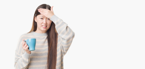 Young Chinese woman over isolated background driking cup of coffee stressed with hand on head, shocked with shame and surprise face, angry and frustrated. Fear and upset for mistake.