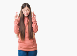 Fototapeta na wymiar Young Chinese woman over isolated background wearing sport sweathshirt smiling crossing fingers with hope and eyes closed. Luck and superstitious concept.