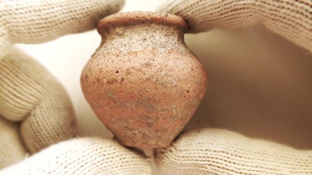 Archeologist inspects tiny ancient authentic clay terracotta amphora