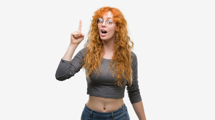 Young redhead woman pointing finger up with successful idea. Exited and happy. Number one.