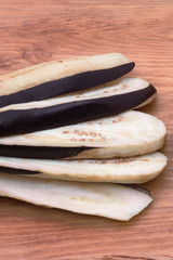 Eggplant slices stacked on top of each other with a fan on a wooden background.