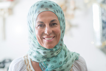 Middle age brunette arabian woman wearing colorful hijab with a happy face standing and smiling with a confident smile showing teeth