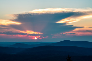 Obraz na płótnie Canvas The sun sets behind a giant thunderstorm cloud in the Appalachian Mountains seen from Spruce Knob in West Virginia