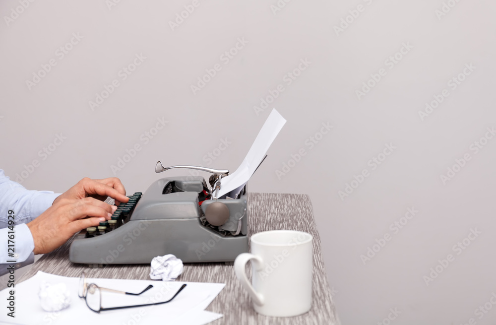Fototapete the man typing on an old-fashioned typewriter. on the table are glasses and there is a mug. neutral 