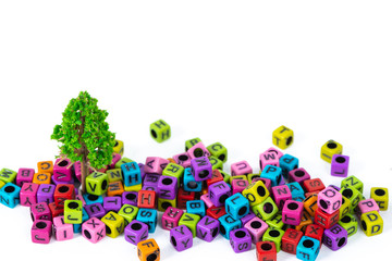 Pile of letter bead or beads with alphabet and little tree on white background.