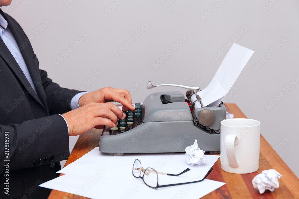 Fototapete the man in a suit typing on an old-fashioned typewriter. on the table are glasses and there is a mug