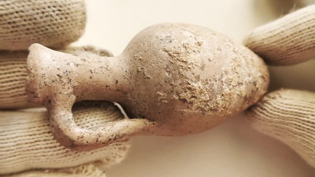 Archeologist inspects tiny ancient authentic clay terracotta amphora