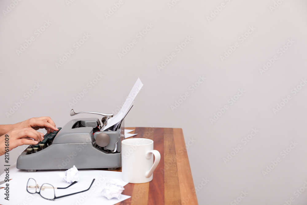 Fototapete the womans hands typing on an old-fashioned typewriter. on the table are glasses and there is a mug.