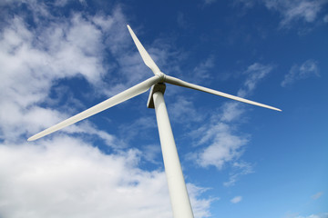 Wind turbine against a blue sky and clouds. Renewable energy