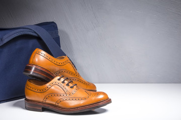 Closeup of Pair of Luxury Male Tanned Full Broggued Oxford Calf Leather Shoes Along Messenger  Blue...