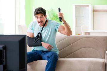 Arm injured man sitting on the sofa watching tv