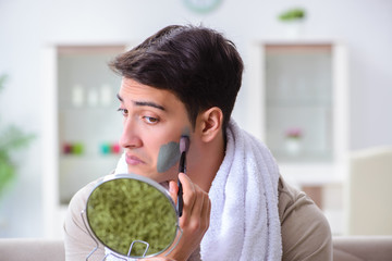 Handsome applying clay mask on face