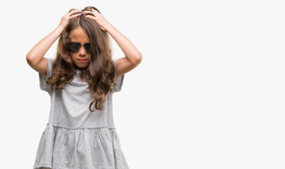 Fototapeta premium Brunette hispanic girl wearing sunglasses suffering from headache desperate and stressed because pain and migraine. Hands on head.