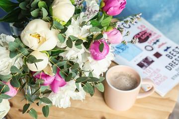 Bouquet with beautiful flowers and cup of coffee on table