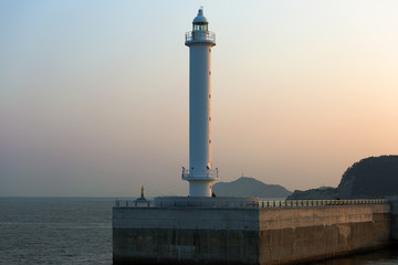 lighthouse at the exit of the port illuminated by the sunset © vasilevich