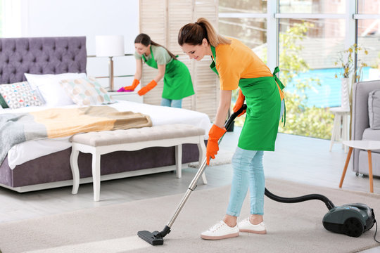 Team of professional janitors in uniform cleaning bedroom