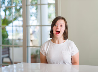 Down syndrome woman at home scared in shock with a surprise face, afraid and excited with fear expression