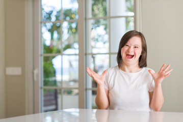 Down syndrome woman at home crazy and mad shouting and yelling with aggressive expression and arms raised. Frustration concept.
