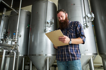 brewer monitoring brewing process at craft beer plant