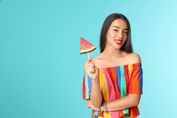 Beautiful young woman posing with watermelon on color background