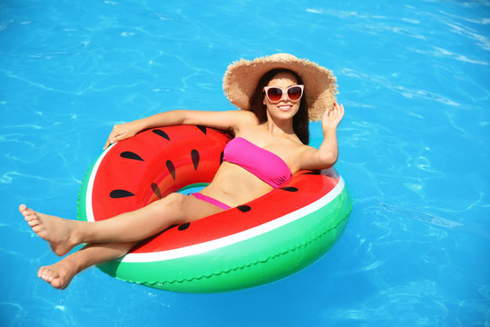 Beautiful young woman with inflatable ring in swimming pool