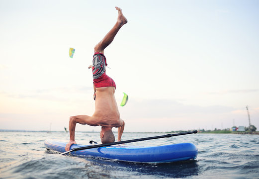 a man on a sup board standing on his head