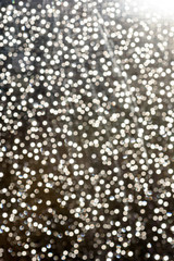 White flecks of defocused light creates a snowfall like bokeh effect in bright white colour for festive christmas concepts and ideas