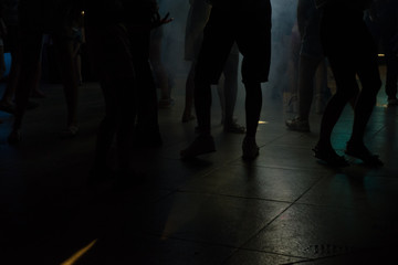 Peoples feet and legs dancing at a nightclub with diffrerent color lights and smoke effects with no...