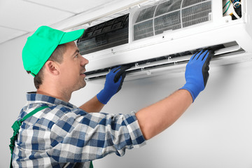 Male technician installing air conditioner indoors