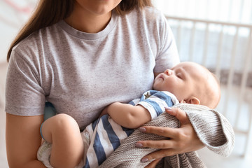 Mother with her sleeping baby at home, closeup view