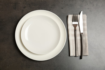 Empty dishware and cutlery on gray background, top view. Table setting