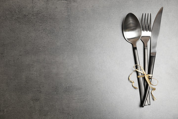 Silver cutlery on gray background, top view. Table setting