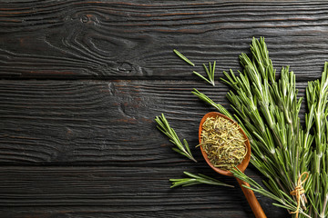 Spoon with dried rosemary and twigs on wooden table, top view