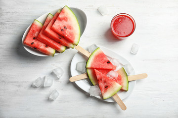 Flat lay composition with watermelon popsicles and ice cubes on white wooden background © New Africa