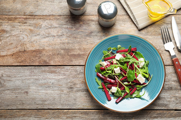 Plate with delicious beet salad on wooden table, top view