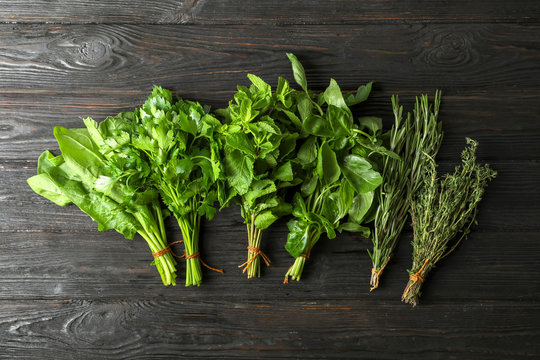 Different fresh herbs on wooden table, top view