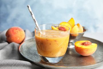 Tasty peach smoothie in glass and fresh fruit on table