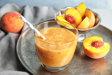 Tasty peach smoothie in glass and fresh fruit on table
