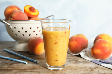 Tasty peach smoothie in glass on wooden table