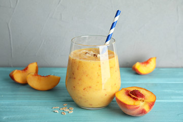 Tasty peach smoothie in glass and fresh fruit on table
