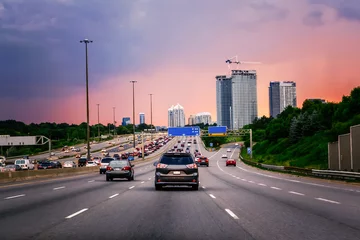Foto op Plexiglas Night traffic. Cars on highway road at sunset evening in typical busy american city. Beautiful amazing night urban view with red, yellow and blue sky clouds. Sundown in downtown. © anoushkatoronto
