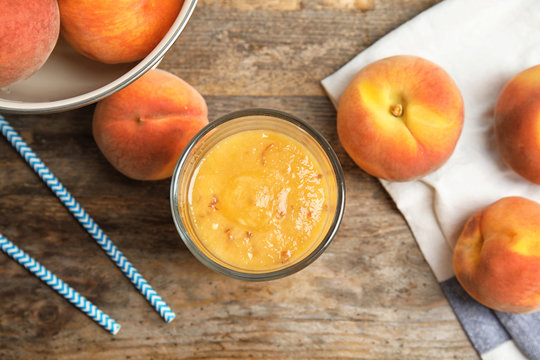 Tasty peach smoothie in glass on table, top view