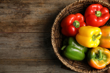 Bowl with ripe paprika peppers on wooden background, top view